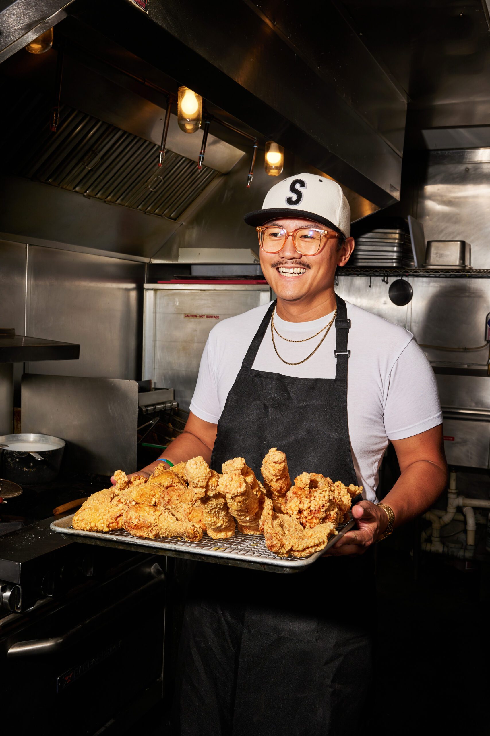 a smiling man holding a tray of fried chicken